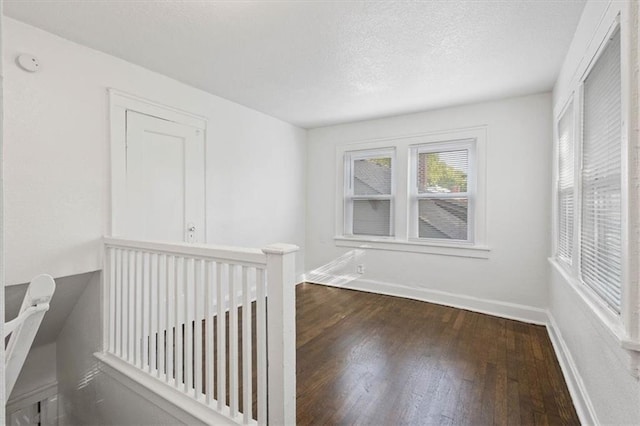 unfurnished room featuring a textured ceiling and dark hardwood / wood-style flooring