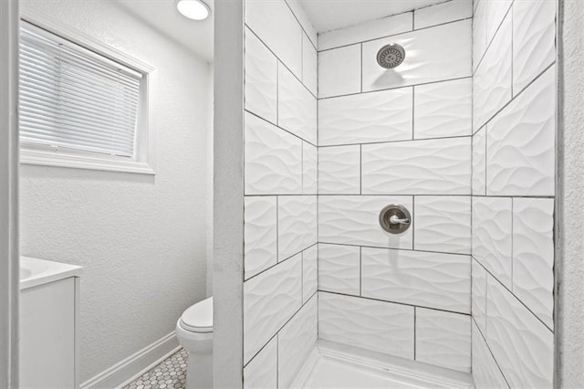 bathroom featuring a tile shower and toilet