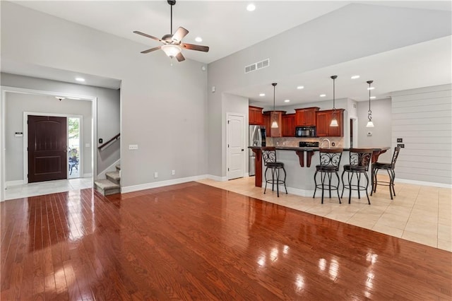 living room featuring light wood-type flooring, lofted ceiling, sink, and ceiling fan