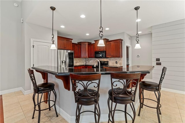 kitchen with stainless steel fridge, a center island with sink, pendant lighting, light tile patterned floors, and decorative backsplash