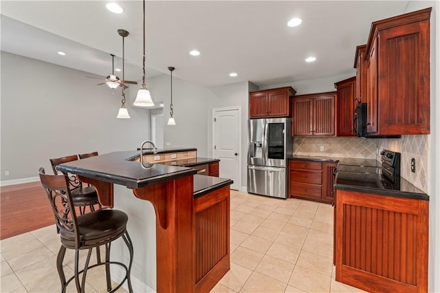 kitchen with backsplash, black appliances, an island with sink, ceiling fan, and pendant lighting