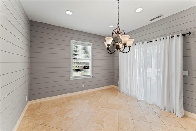 tiled empty room with wood walls and an inviting chandelier