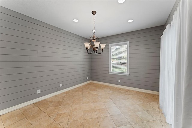 tiled spare room with wood walls and a notable chandelier