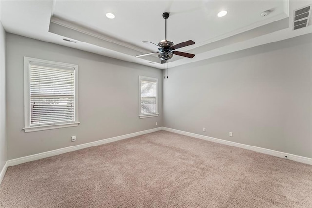 unfurnished room with ceiling fan, ornamental molding, light carpet, and a tray ceiling