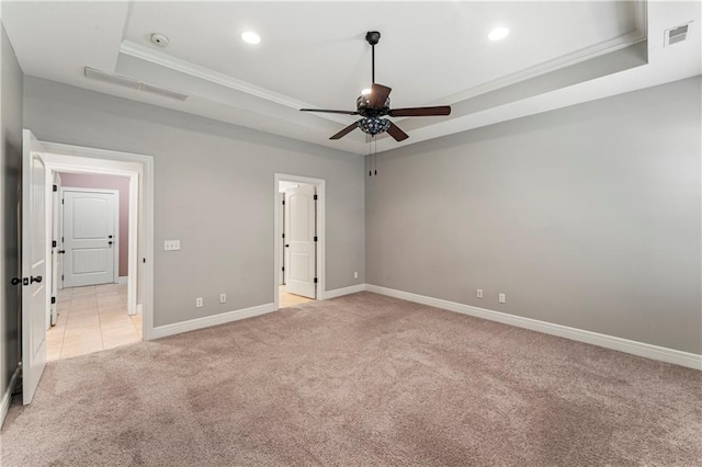 unfurnished bedroom featuring a raised ceiling, ceiling fan, ornamental molding, and light colored carpet