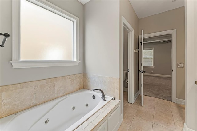 bathroom with tile patterned flooring, toilet, and tiled tub