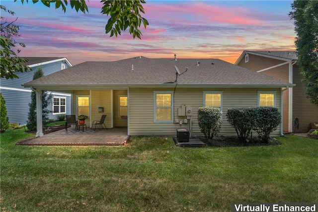 back house at dusk with a lawn and a patio