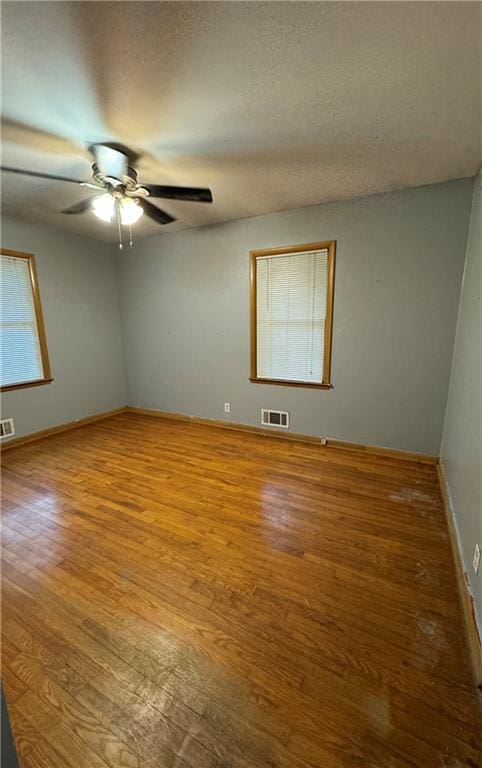 empty room with hardwood / wood-style floors, a textured ceiling, and ceiling fan