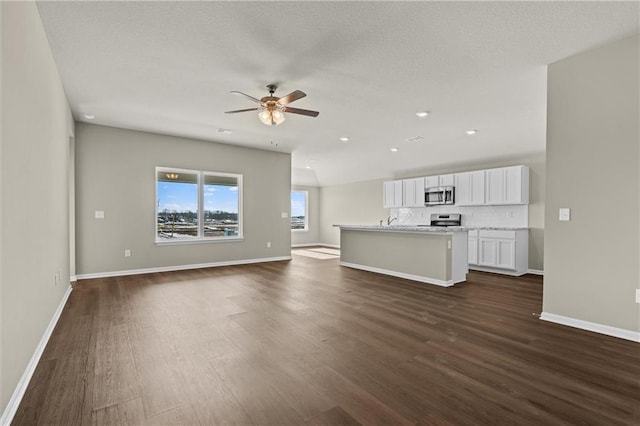 unfurnished living room with ceiling fan, dark hardwood / wood-style flooring, and sink