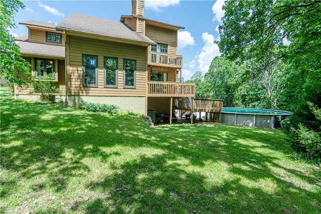 rear view of house with a pool side deck and a lawn