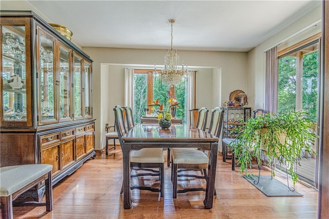 dining area with plenty of natural light, light hardwood / wood-style flooring, and a notable chandelier