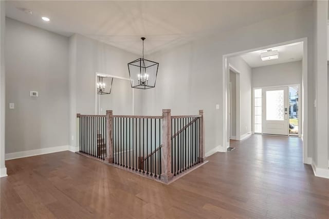 hall with dark wood-type flooring and a chandelier