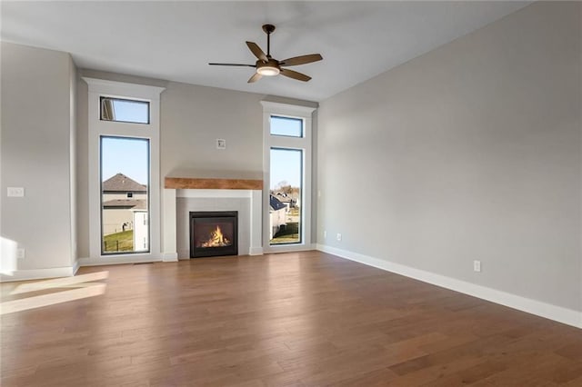 unfurnished living room with plenty of natural light, dark hardwood / wood-style floors, and ceiling fan