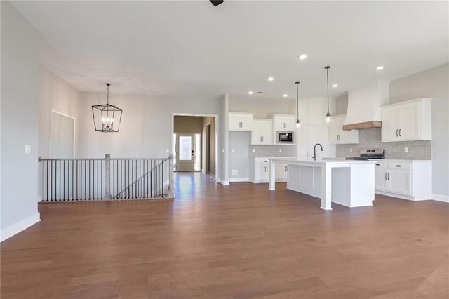 kitchen featuring a center island with sink, white cabinets, pendant lighting, and custom exhaust hood