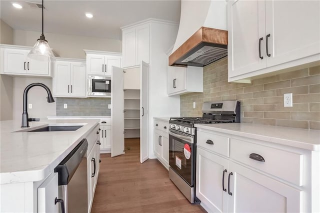 7090 NW Forest Lakes Dr, Parkville, MO 64152 - kitchen featuring stainless steel appliances, custom exhaust hood, light wood-style floors, white cabinets, and pendant lighting