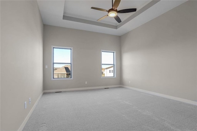 carpeted empty room featuring a tray ceiling and ceiling fan