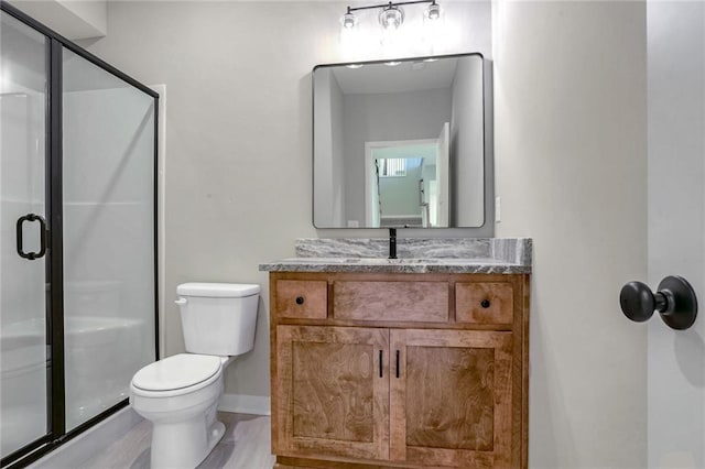 bathroom featuring vanity, toilet, and a shower with shower door