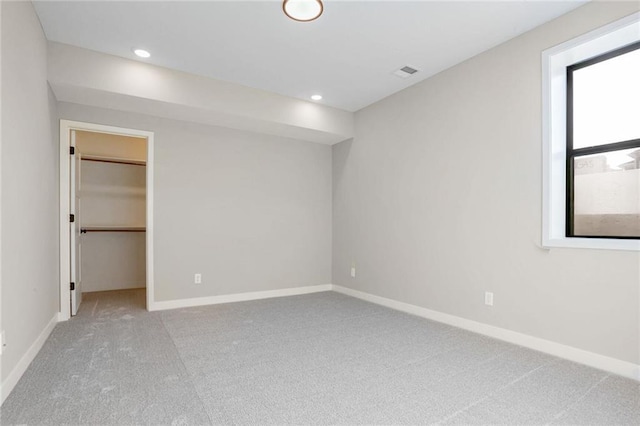 unfurnished bedroom featuring light carpet, a walk in closet, and a closet