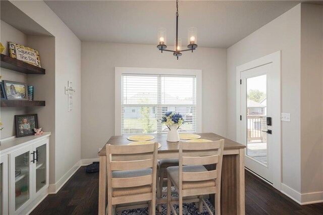 dining area with a healthy amount of sunlight, an inviting chandelier, and dark hardwood / wood-style floors