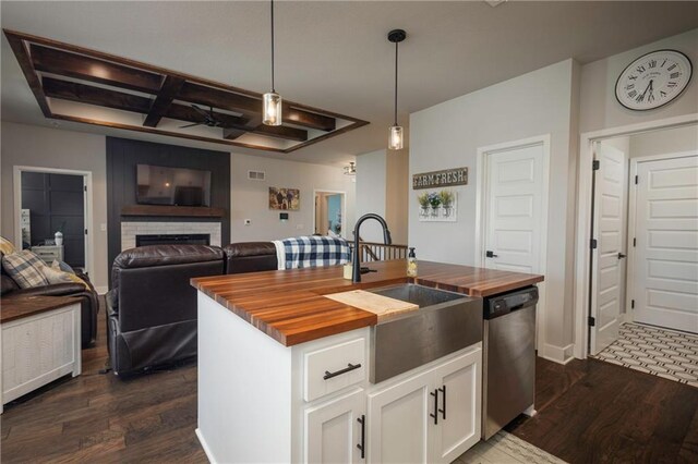 kitchen featuring a fireplace, an island with sink, stainless steel dishwasher, hanging light fixtures, and white cabinetry