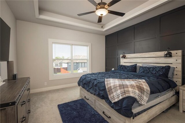 carpeted bedroom featuring a raised ceiling and ceiling fan