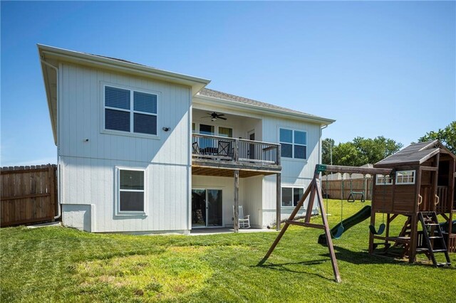 rear view of house featuring a balcony, a playground, ceiling fan, and a lawn