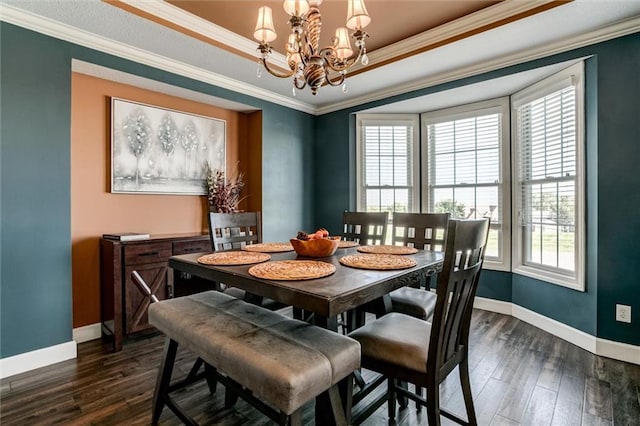 dining space with ornamental molding, a notable chandelier, a healthy amount of sunlight, and dark hardwood / wood-style flooring