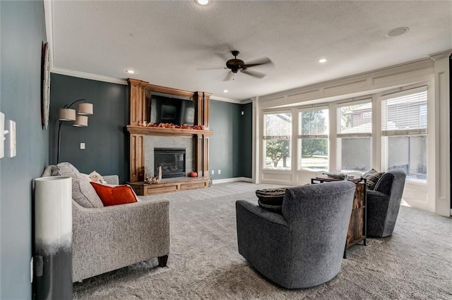 carpeted living room featuring a textured ceiling, crown molding, a fireplace, and ceiling fan