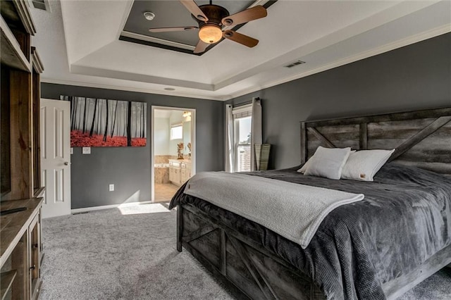 carpeted bedroom featuring ceiling fan, a tray ceiling, crown molding, and ensuite bathroom