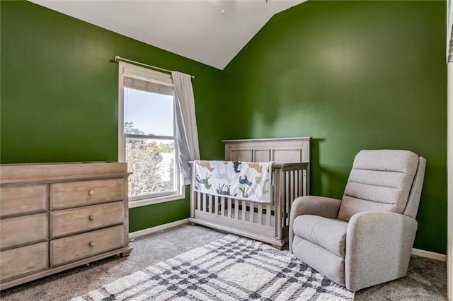 carpeted bedroom featuring lofted ceiling and a crib