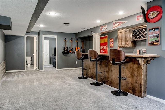 bar featuring a textured ceiling and light colored carpet