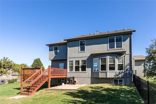 rear view of house with a yard, a wooden deck, and a patio area