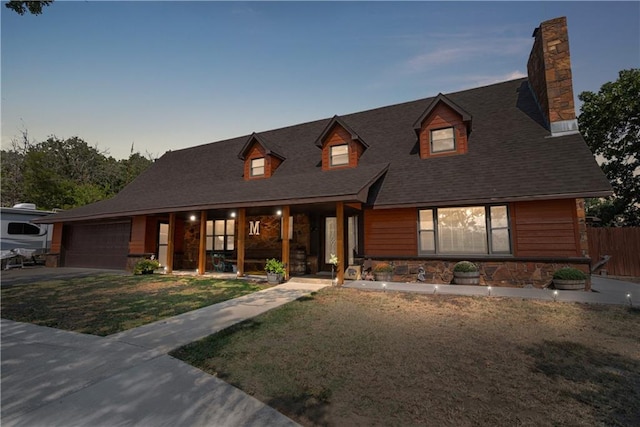 view of front facade featuring a garage, covered porch, and a lawn