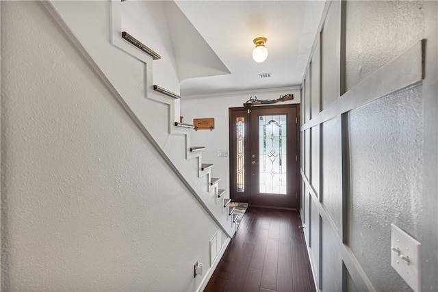 foyer with crown molding and dark wood-type flooring