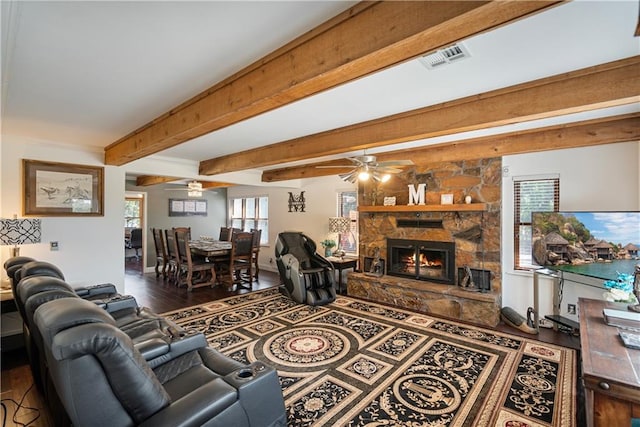 living room featuring ceiling fan, dark hardwood / wood-style floors, beamed ceiling, and a fireplace