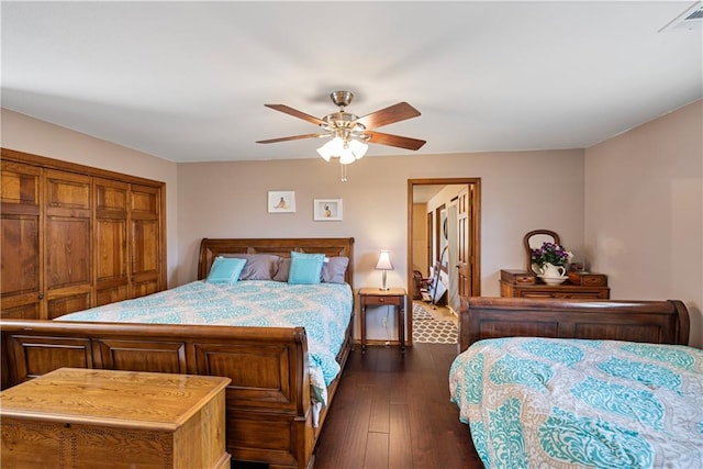 bedroom with dark wood-type flooring, ceiling fan, and a closet