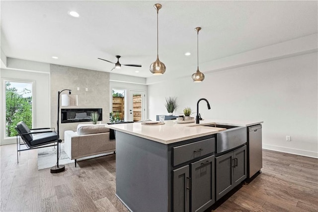 kitchen featuring ceiling fan, an island with sink, stainless steel dishwasher, and a wealth of natural light