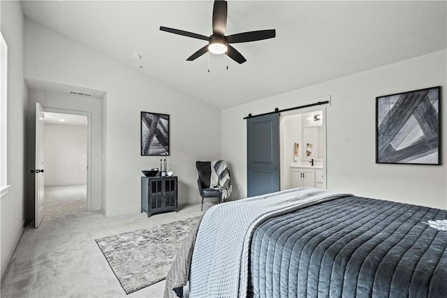 bedroom featuring a barn door, connected bathroom, lofted ceiling, ceiling fan, and carpet