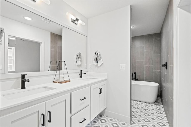 bathroom with a bathing tub, vanity, and tile patterned floors