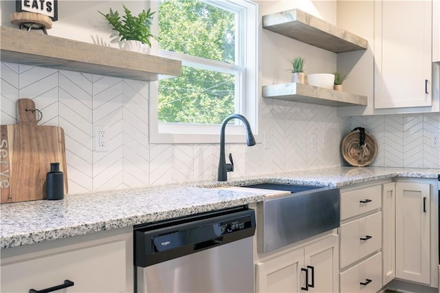 kitchen featuring light stone countertops, white cabinetry, tasteful backsplash, and stainless steel dishwasher