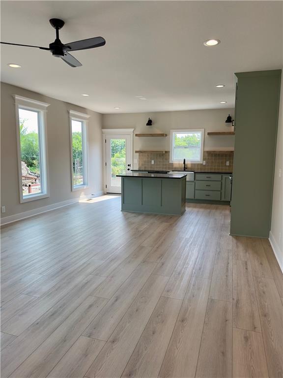 unfurnished living room with ceiling fan, sink, and light hardwood / wood-style floors