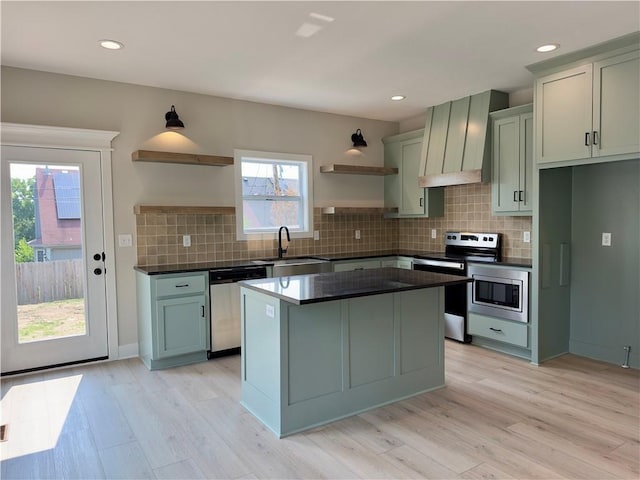 kitchen featuring light hardwood / wood-style floors, premium range hood, appliances with stainless steel finishes, and sink