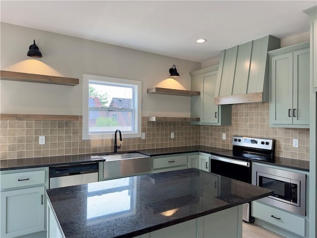 kitchen with appliances with stainless steel finishes, dark stone countertops, tasteful backsplash, light hardwood / wood-style flooring, and sink