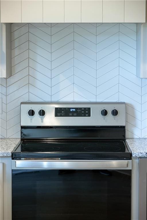 room details with light stone countertops, white cabinetry, and stainless steel electric range oven