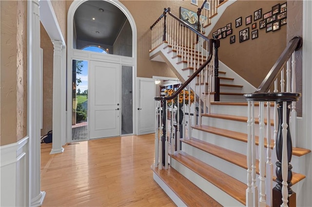 foyer entrance with a high ceiling, decorative columns, and light hardwood / wood-style floors