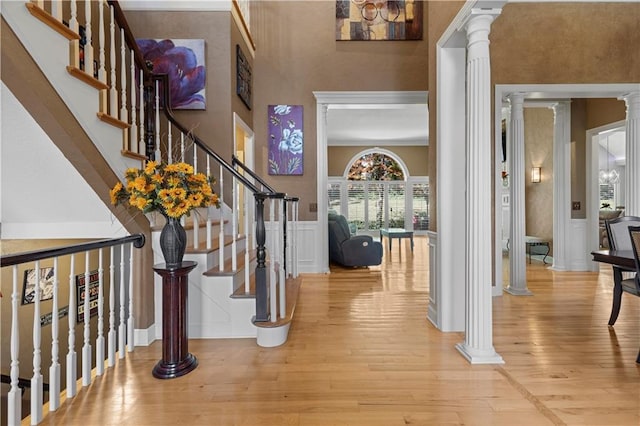 foyer entrance featuring ornamental molding, light wood-type flooring, and ornate columns