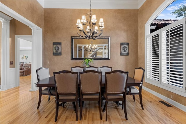 dining space with a notable chandelier, decorative columns, and light hardwood / wood-style floors