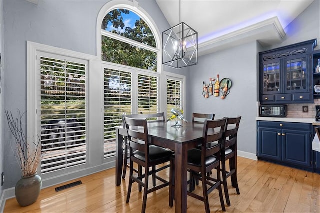 dining space with a wealth of natural light, vaulted ceiling, light wood-type flooring, and a chandelier