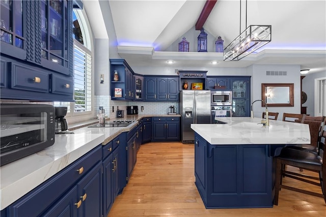 kitchen with decorative light fixtures, blue cabinetry, light hardwood / wood-style floors, an island with sink, and stainless steel appliances