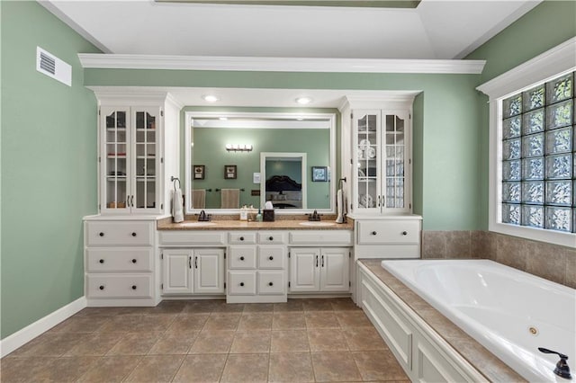 bathroom featuring tile patterned flooring, a relaxing tiled tub, and vanity